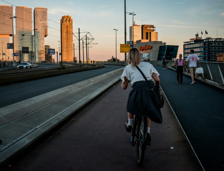 a woman riding a bike down a street next to tall buildings