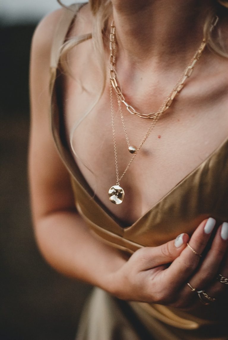 woman in gold sleeveless dress wearing gold necklace